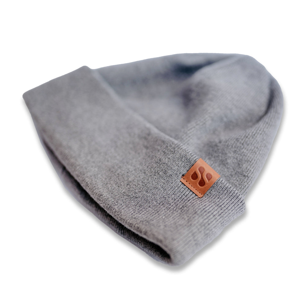 Gray SafeSleeve Beanie with brown leather patch logo, displayed folded on white background, detail view.