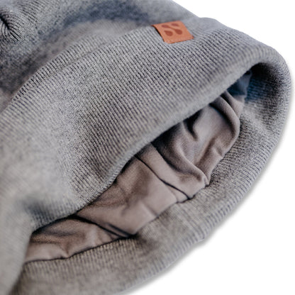 SafeSleeve Beanie pulled back to reveal layered gray fabric interior lining and brown logo patch detail.