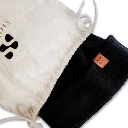 SafeSleeve Beanie in black and cream displayed with drawstring storage bag, showing product label detail.