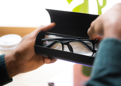 Person opening black case to reveal Ocushield Clear blue light glasses with black frames inside.