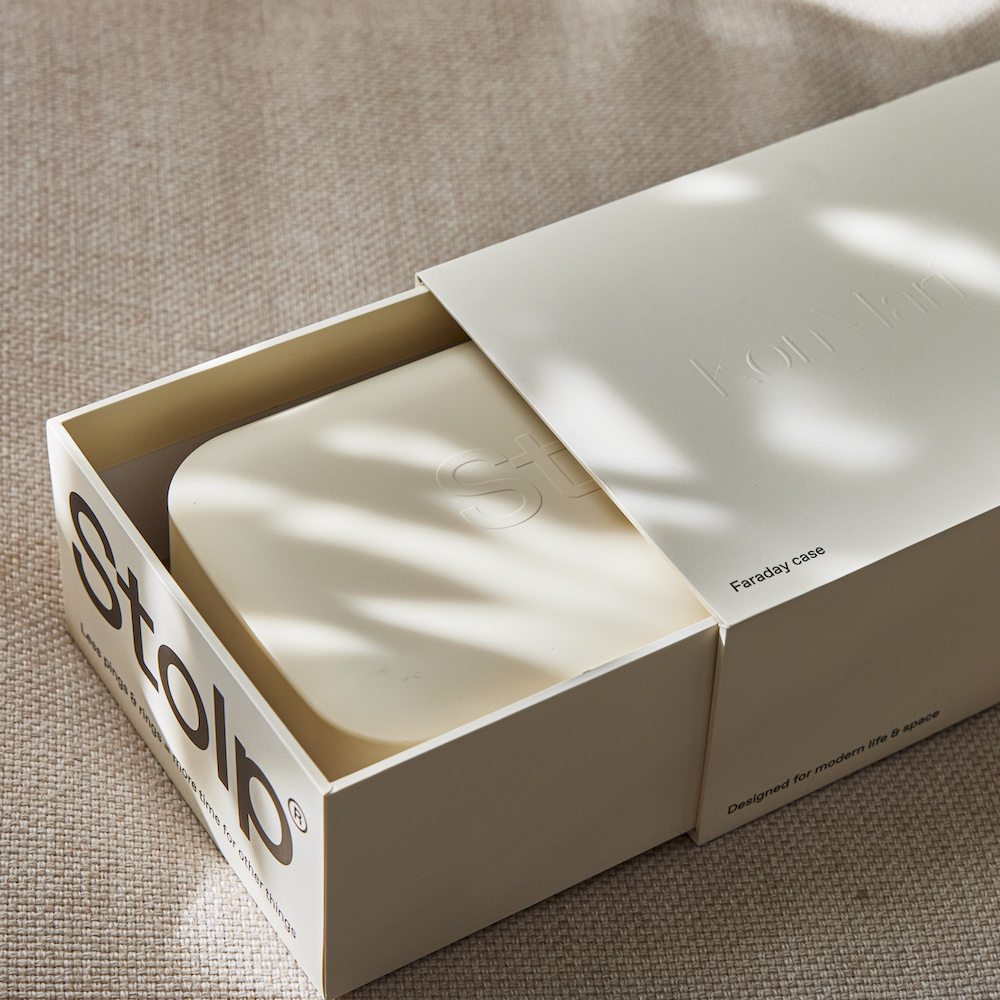 Close-up of the sand-colored Bagby Stolp x KonMari packaging slid open to reveal the Faraday box inside, with embossed logos.