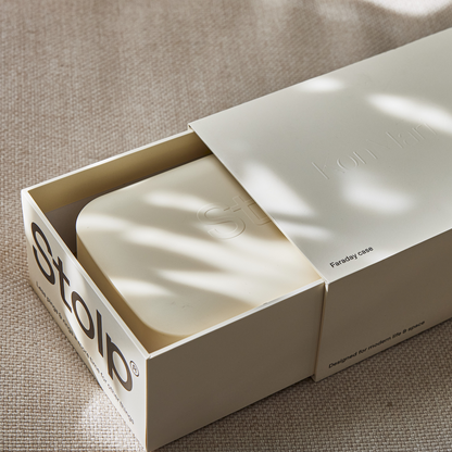 Close-up of the sand-colored Bagby Stolp x KonMari packaging slid open to reveal the Faraday box inside, with embossed logos.