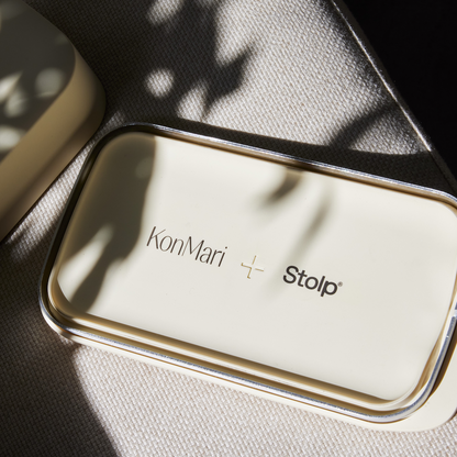 Close-up of the sand-colored Faraday tray's metal-rimmed interior, engraved with the KonMari and Bagby Stolp logos.
