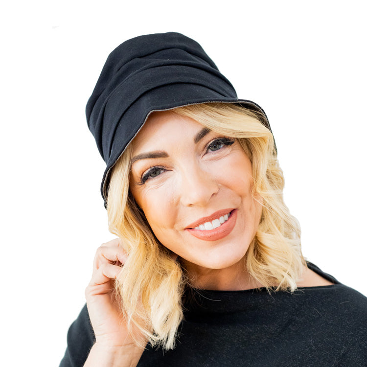 Woman wearing black TRU47 cotton double knit bucket hat, front view, smiling at camera against white background.