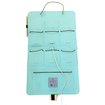 Interior view of a mint-green Bagby FAMILY organizer showing empty pockets, elastic cord closures and a charging cable routed through.