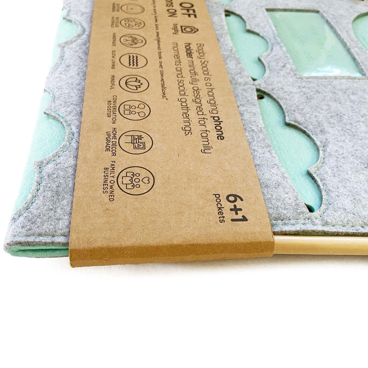 Close-up of the mint-green Bagby FAMILY organizer's cloud-shaped pockets and embossed window, partly wrapped in its kraft band.