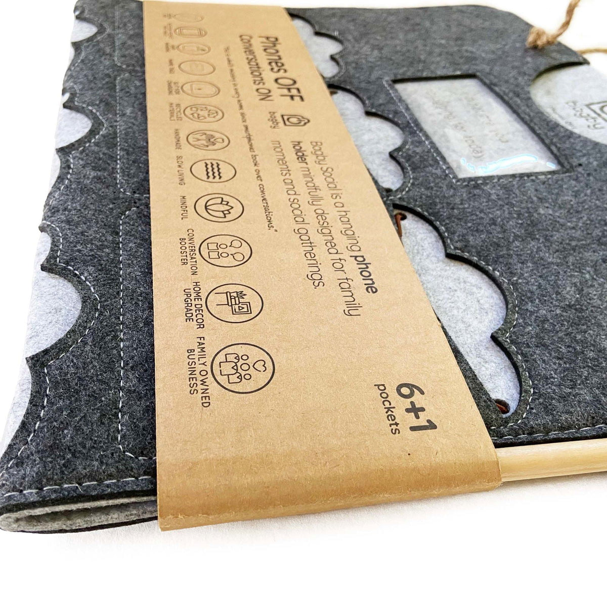 Close-up of a dark charcoal Bagby FAMILY organizer's cloud-shaped pockets and embossed window in its kraft band with rope hanger.