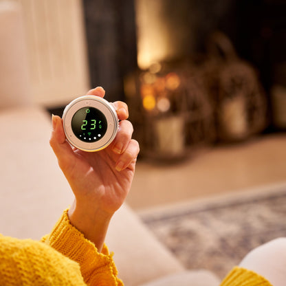 Hand holding Bebcare Low-EMF digital audio baby monitor displaying 23°C temperature on screen.