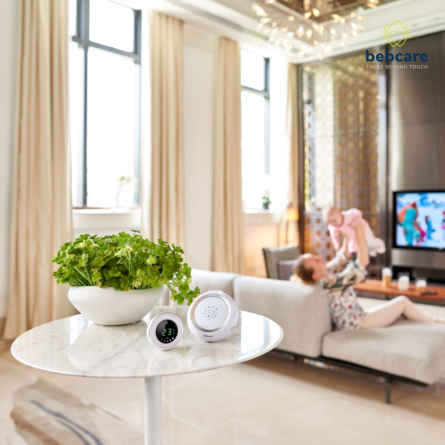 Bebcare baby monitor units displayed on marble table with potted plant in modern living room scene.