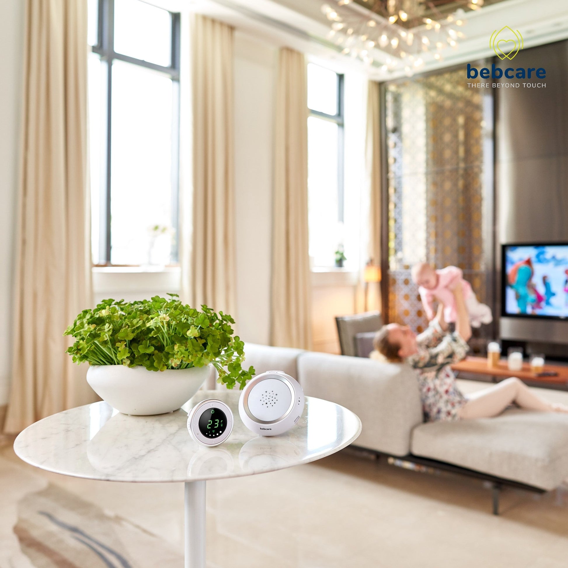 Bebcare baby monitor units displayed on marble table with potted plant in modern living room scene.
