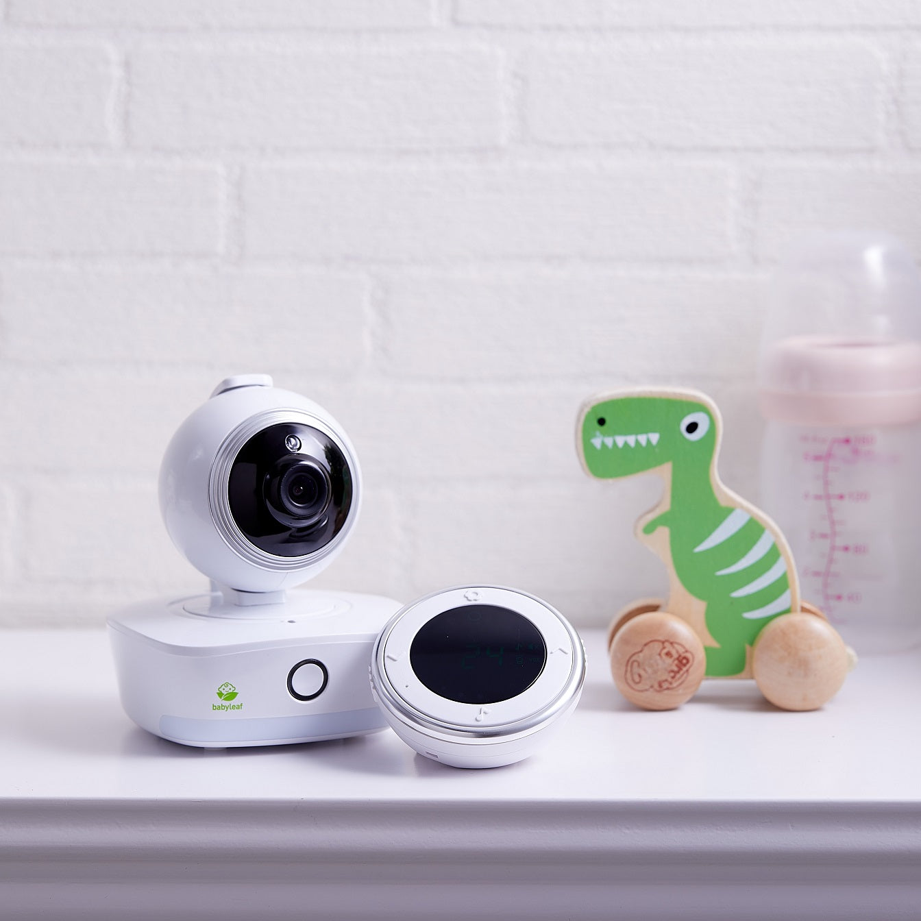 Bebcare Low-EMF IQ WiFi HD Baby Monitor displayed with parent unit and camera on white shelf beside toys and bottle.