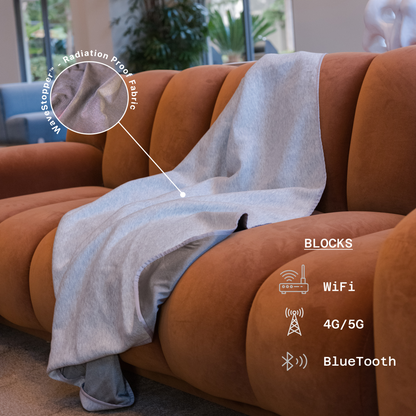 HAVN WaveStopper™ Blanket draped over tan sofa, highlighting radiation proof, WiFi, 4G/5G, and Bluetooth blocking features.