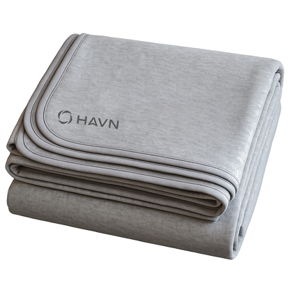 HAVN WaveStopper™ Blanket folded in layers showing light and dark gray fabric with piping detail and logo.