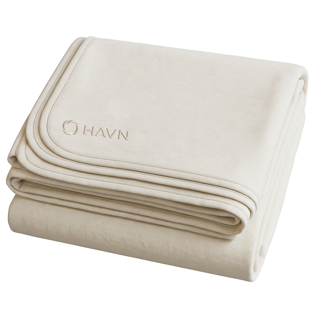 Folded HAVN WaveStopper™ Blanket in cream displaying embroidered logo and layered fabric construction.