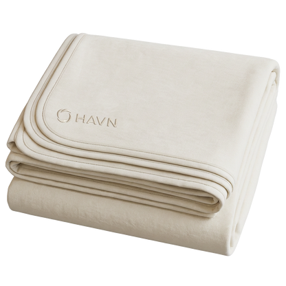 Folded HAVN WaveStopper™ Blanket in cream displaying embroidered logo and layered fabric construction.