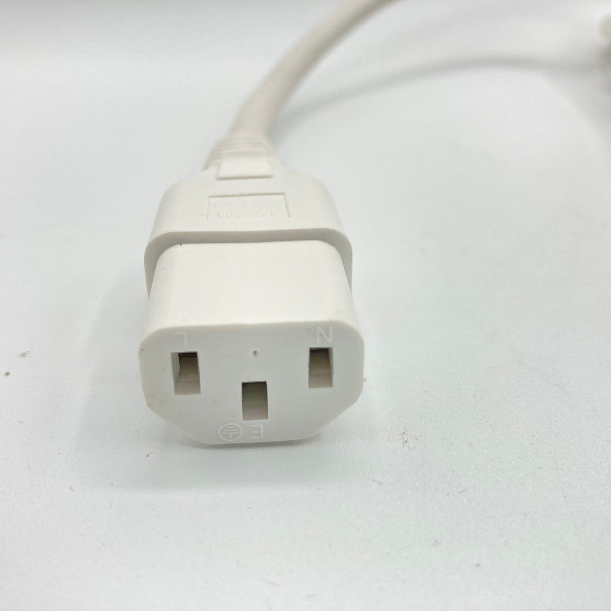 Close view of a white C13 appliance connector at the end of a power cord.