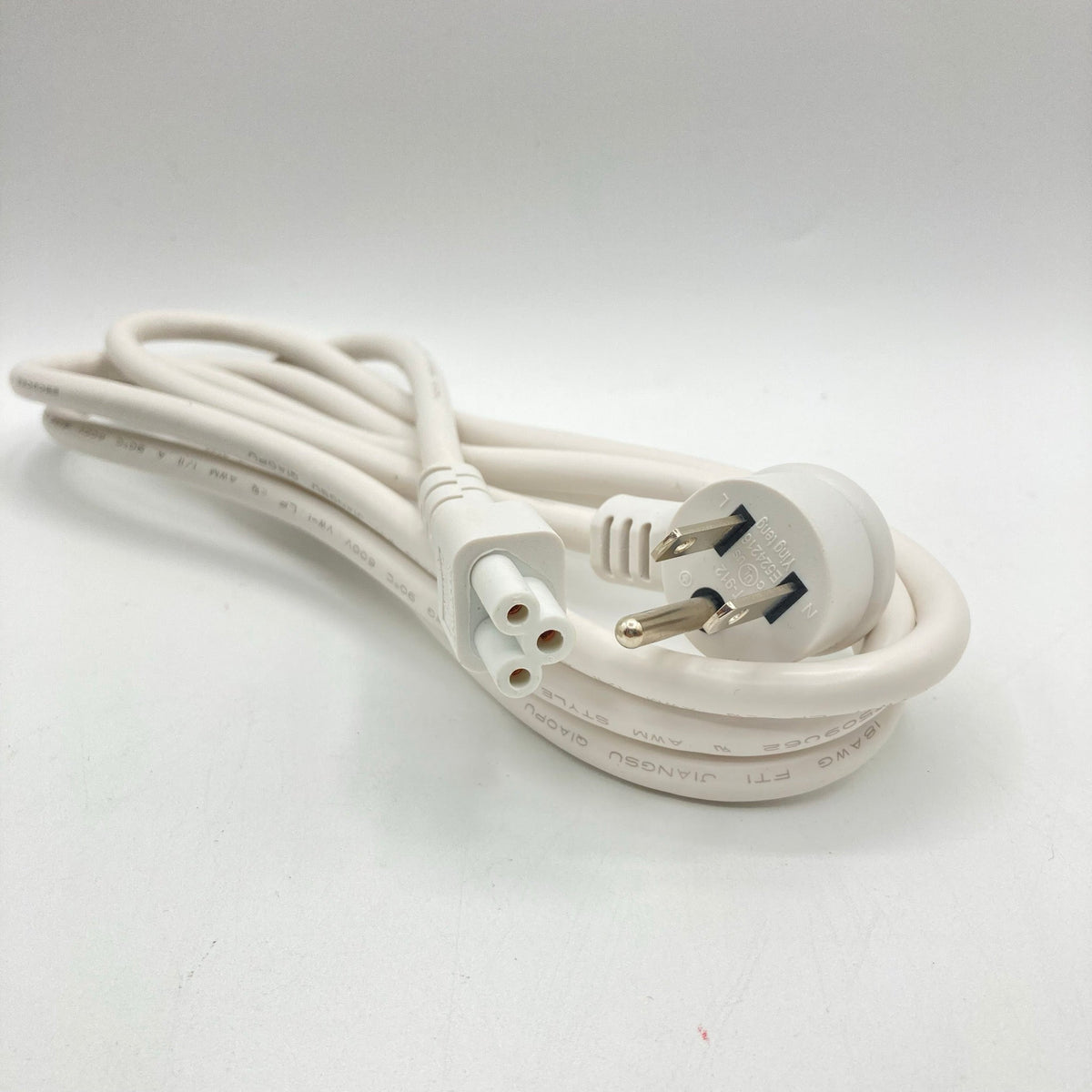 White power cord with an angled grounded plug and a C5 clover-leaf connector, coiled on a white surface.