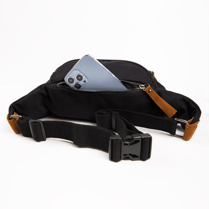 SYB Canvas Traveler cross body fanny pack in black with brown leather accents, displayed open with smartphone visible in top pocket.
