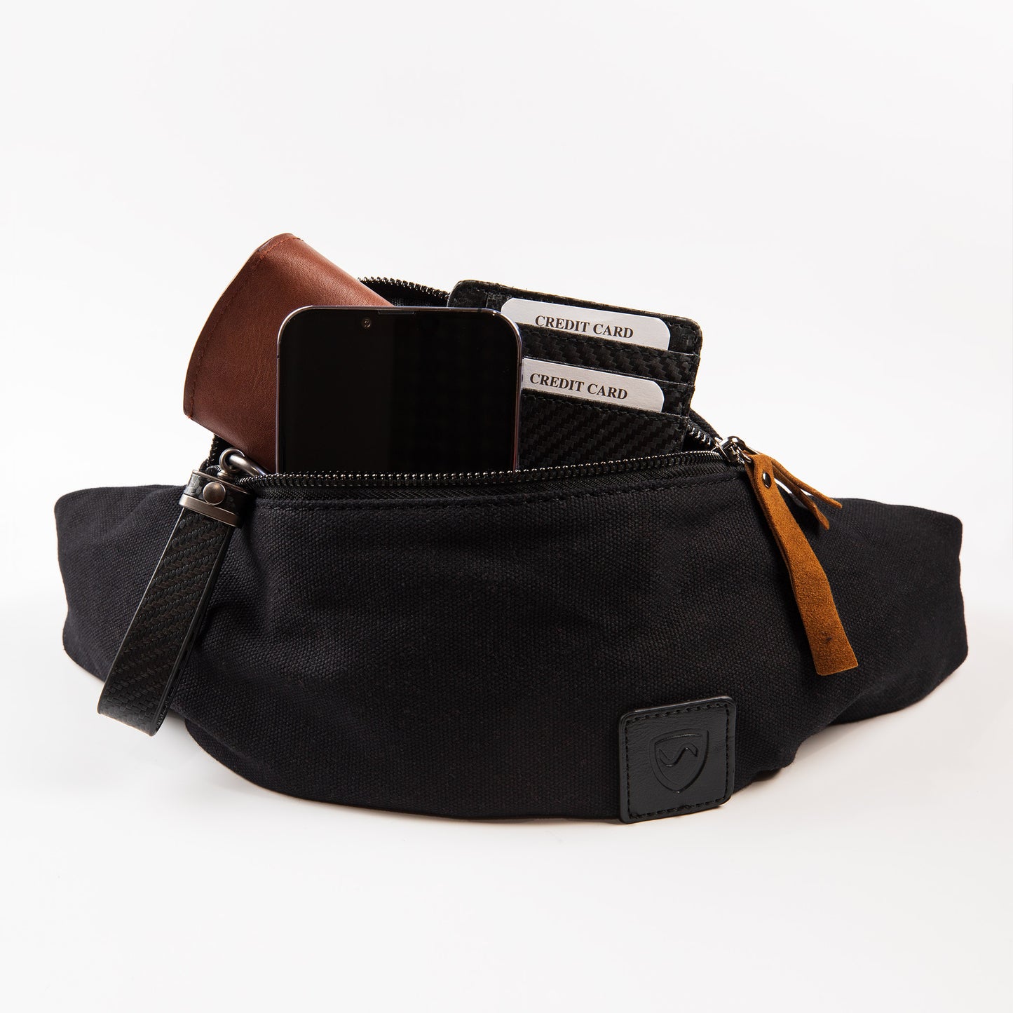 SYB Canvas Traveler fanny pack open to display interior storage with smartphone, brown wallet, and credit cards visible.