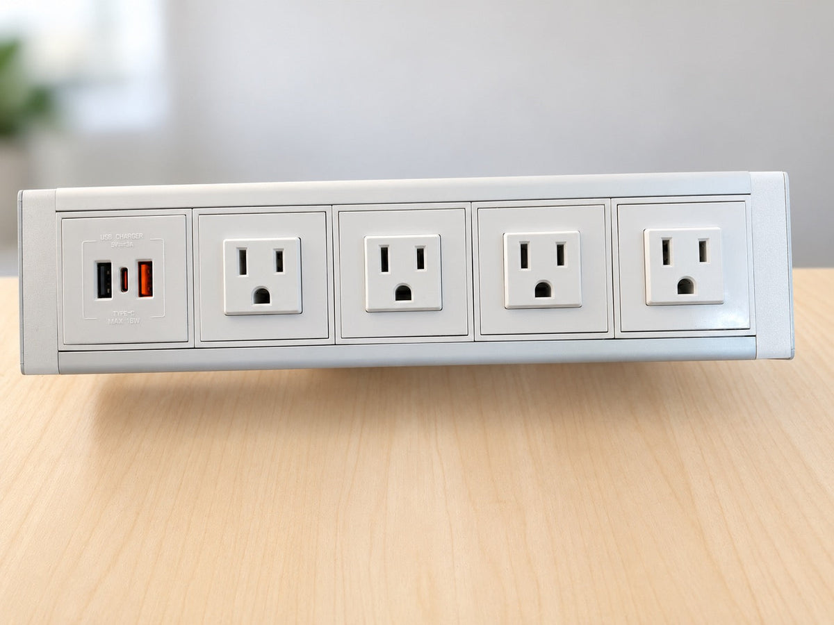 Front view of a white and silver desktop power dock showing four grounded AC outlets and a panel with USB-A and USB-C ports.