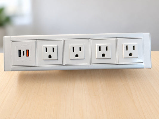 Front view of a white and silver desktop power dock showing four grounded AC outlets and a panel with USB-A and USB-C ports.