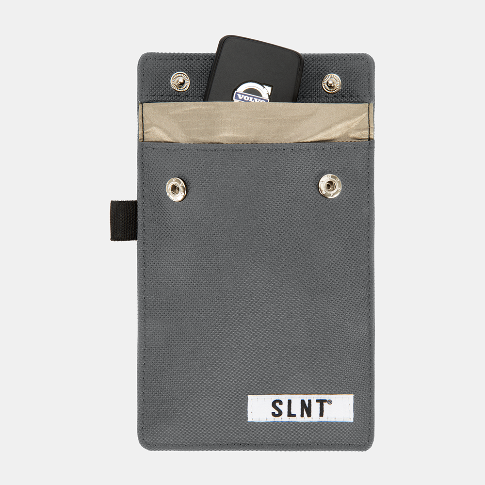Gray Faraday Key Fob Bag with tan interior pocket, metal grommets, black strap, and SLNT brand label, containing a black key fob.