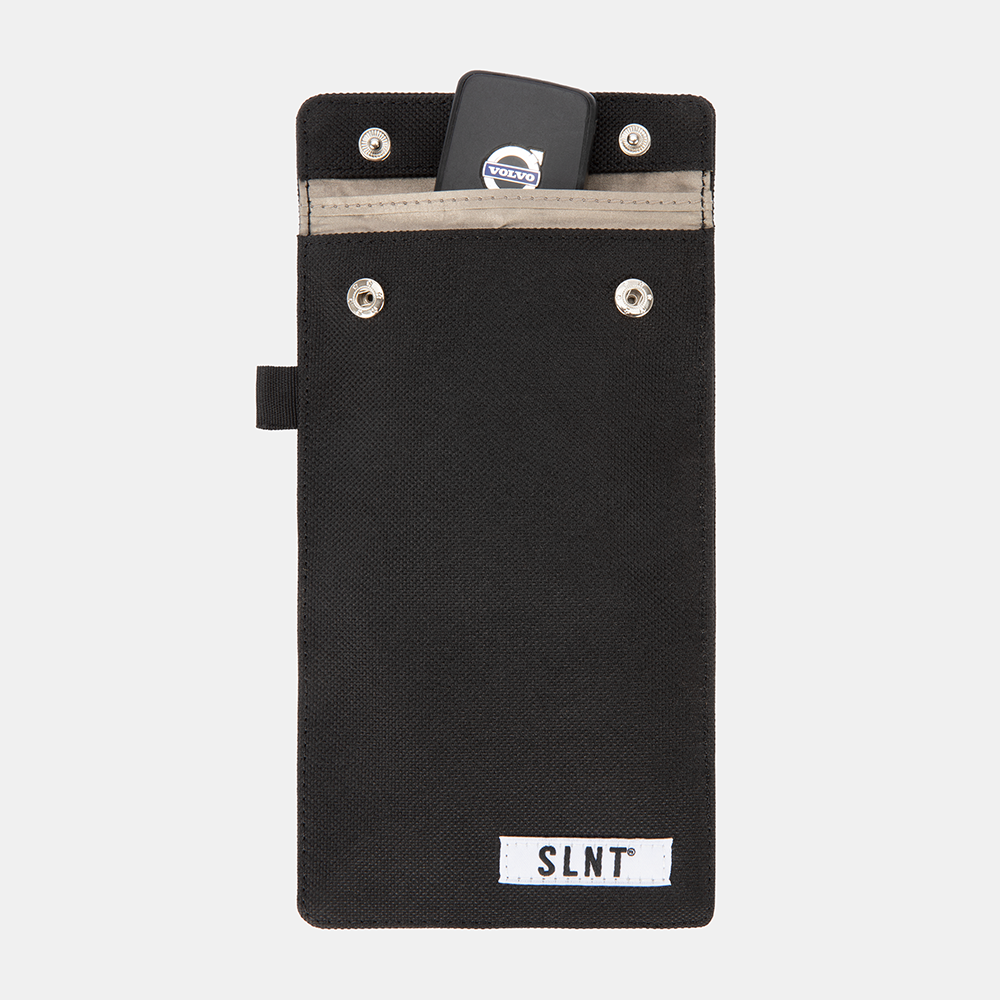 Black Faraday Key Fob Bag with Volvo key fob inside top pocket, showing front view with SLNT label and metal snaps.
