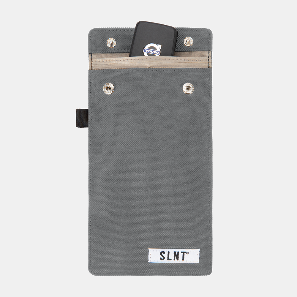 Gray Faraday Key Fob Bag with Volvo key fob inserted in top pocket, displaying SLNT branding and metal snap closures.
