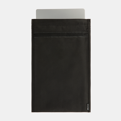 SLNT Faraday Laptop Bag in black with silver laptop partially inserted into the open top compartment.