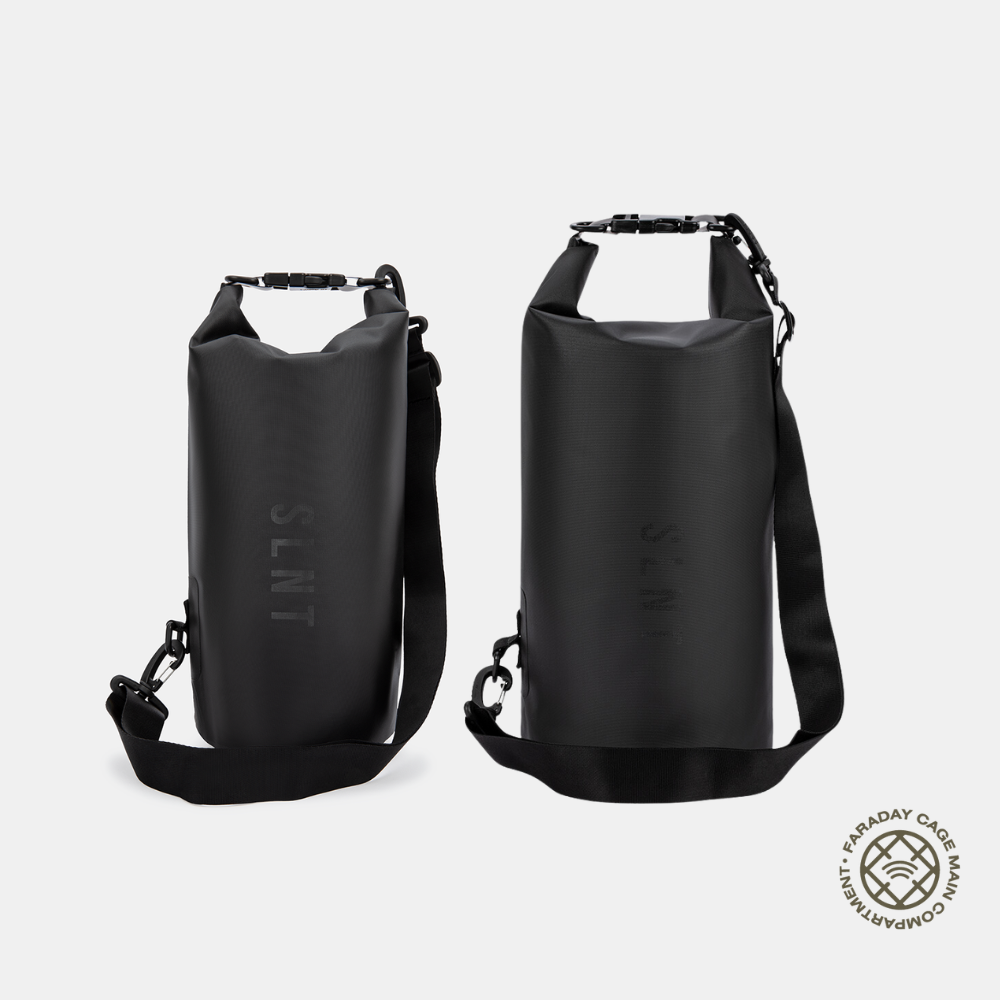 Two black SLNT Faraday dry bags in different sizes displayed side by side with shoulder straps and roll-top closures.