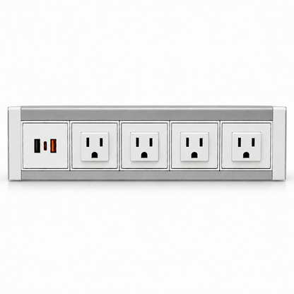 White and silver metal power dock with four AC outlets and a USB charging panel, resting on a light wood desk.