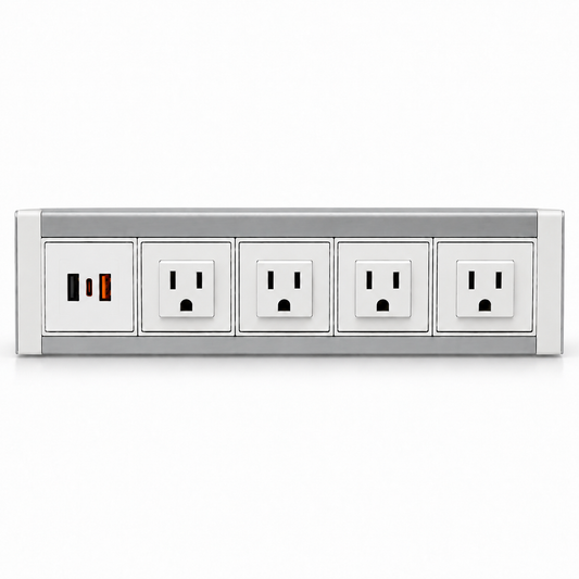 White and silver metal power dock with four AC outlets and a USB charging panel, resting on a light wood desk.