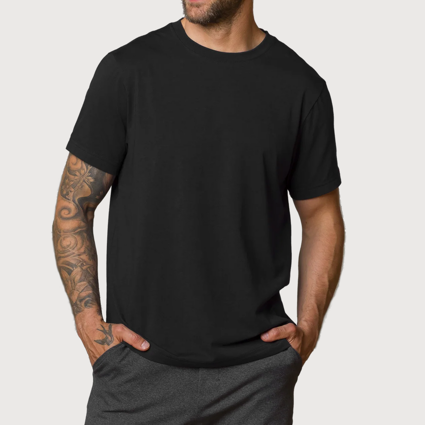 Man wearing black HAVN WaveStopper™ T-Shirt 2.0 with gray shorts, hands in pockets, front view.