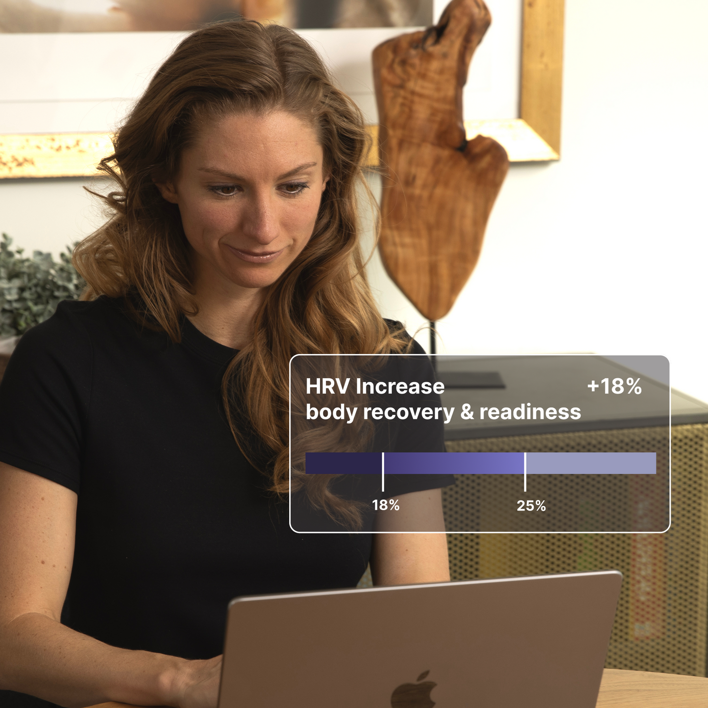 Woman wearing black HAVN WaveStopper™ T-Shirt 2.0 at desk with laptop, displaying HRV increase data showing +18% body recovery and readiness improvement.