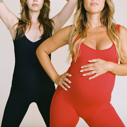 Two women wearing Juunaday Even Flow Unitards in black and red, demonstrating the fitted silhouette and versatile styling options.
