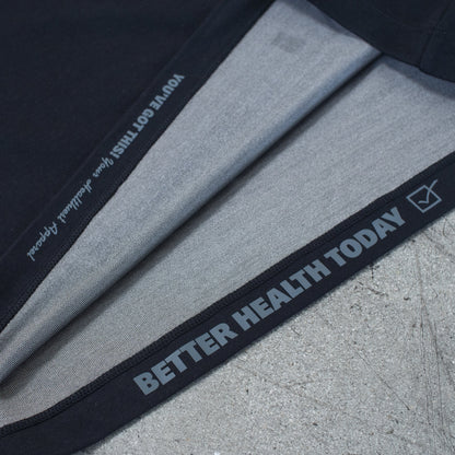 Folded HAVN WaveStopper™ T-Shirt 2.0 displaying black waistband with "BETTER HEALTH TODAY" text and gray fabric layers on concrete surface.
