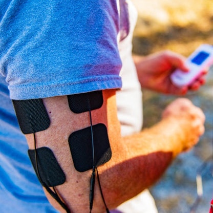 iReliev TENS Electrodes Refill Kit pads applied to person's arm during use outdoors
