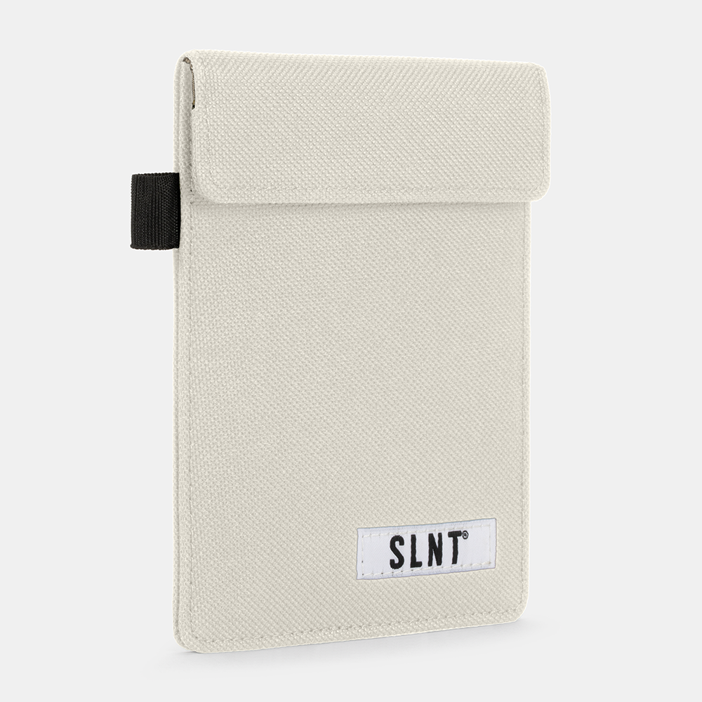 Cream-colored Faraday Key Fob Bag with textured fabric, black tab handle, and SLNT brand label on front.