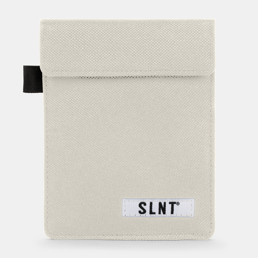 Cream canvas Faraday Key Fob Bag with black fabric loop tab and white SLNT brand label, front view.