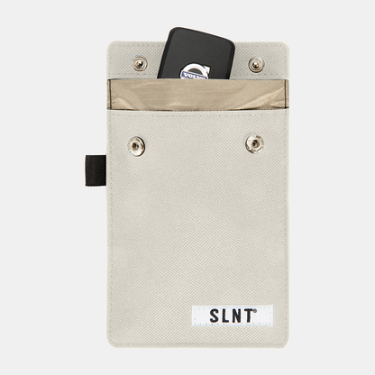 Faraday Key Fob Bag in cream canvas with open flap revealing black key fob inside and tan interior pocket, SLNT branding visible.
