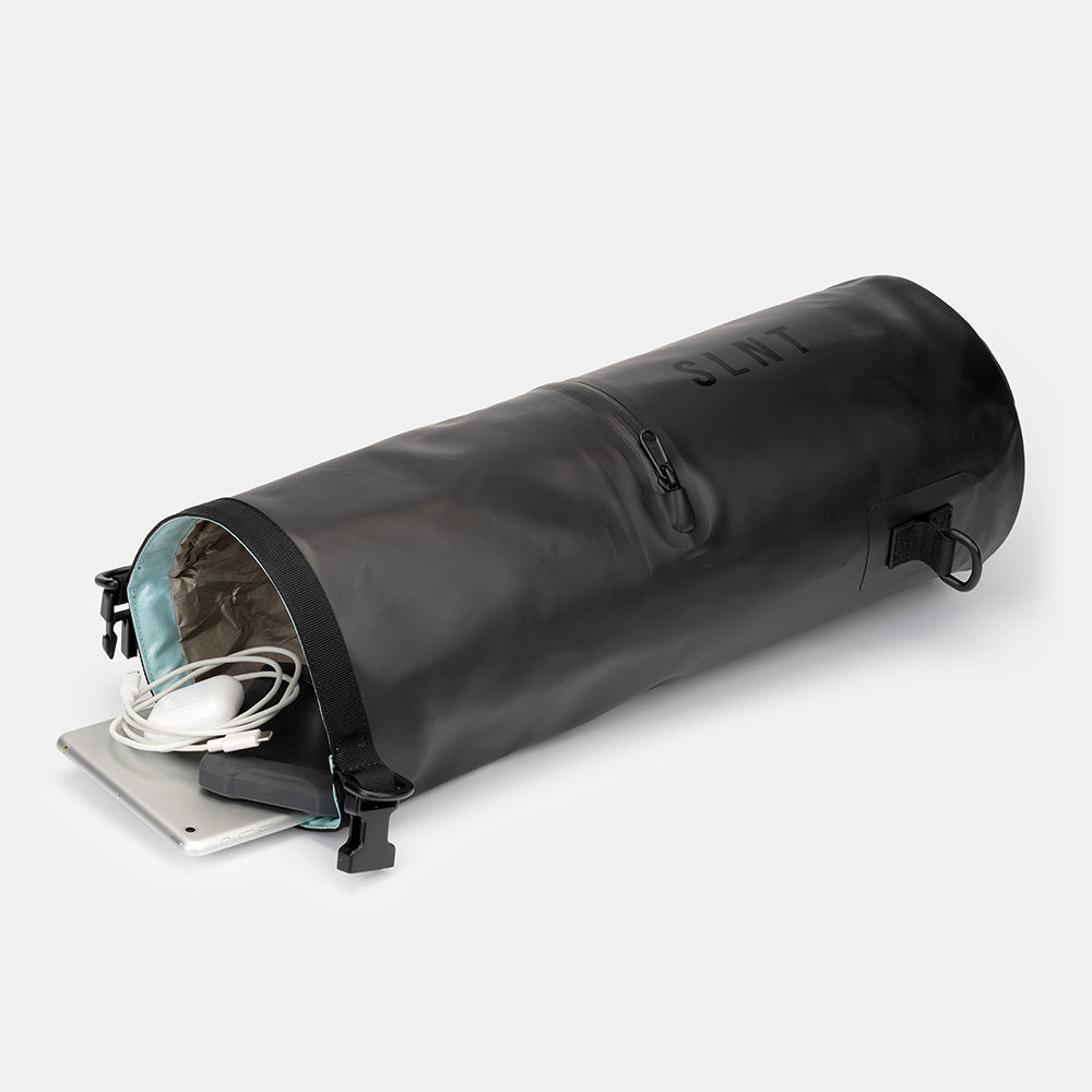 SLNT Faraday Dry Bag open end view showing interior lining, with white cable and tablet device partially inserted.