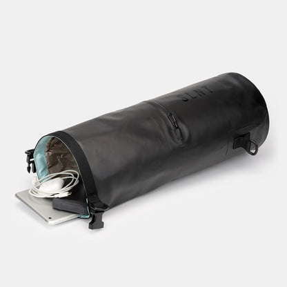 SLNT Faraday Dry Bag open end view showing interior lining, with white cable and tablet device partially inserted.