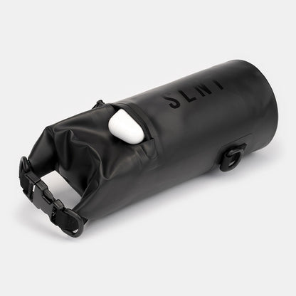 SLNT Faraday Dry Bag with white earbuds inside, rolled closed with black straps and attachment points visible.