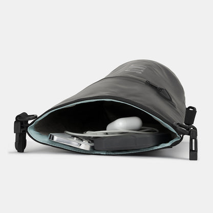 SLNT Faraday Dry Bag open showing interior storage with white wireless earbuds and cable inside.
