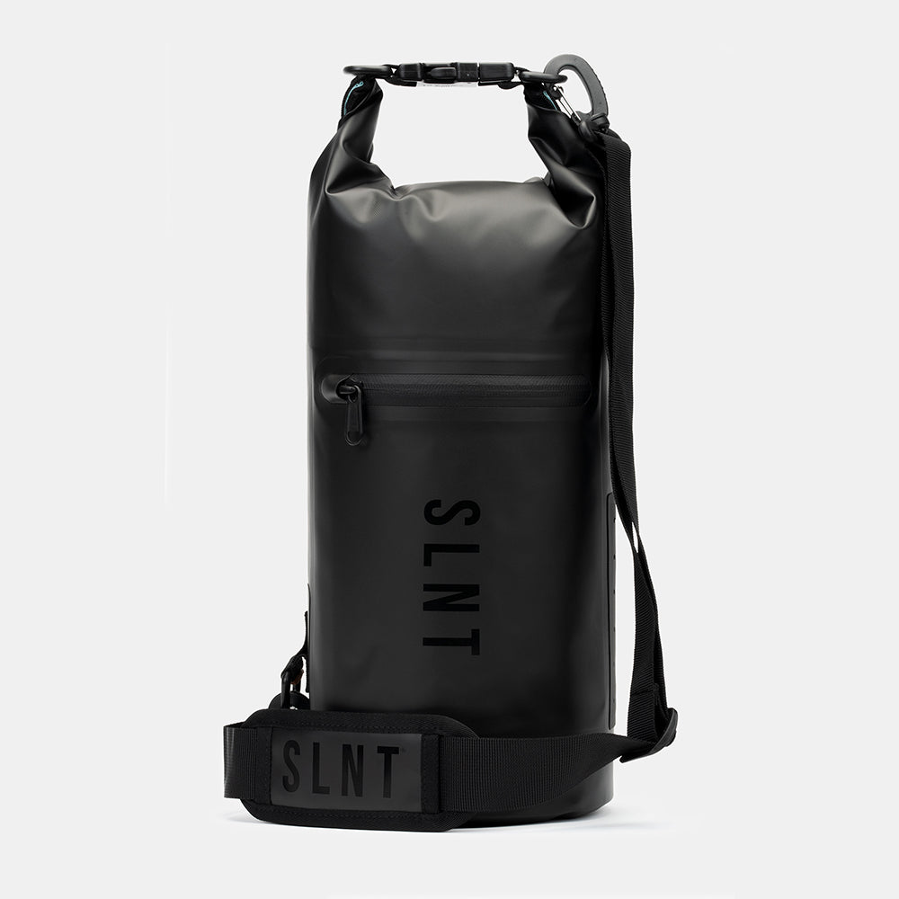 Black SLNT Faraday Dry Bag with rolled top closure, front zipper pocket, shoulder strap, and branded label, shown front view against white background.