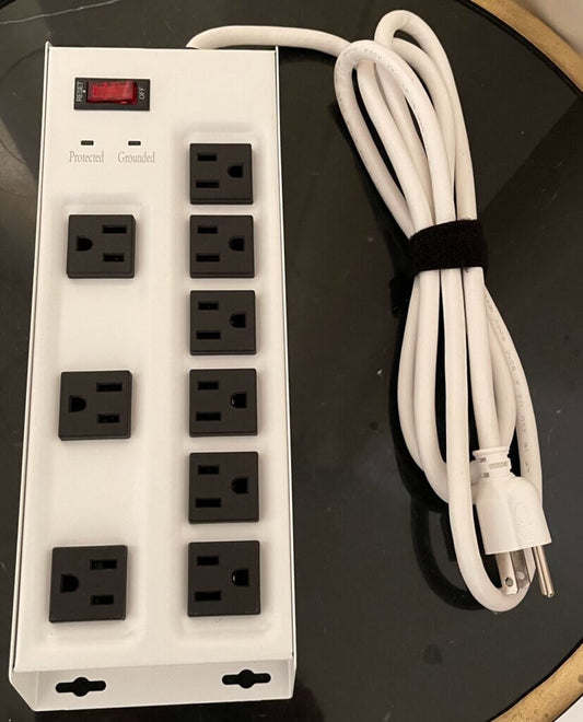 White metal nine-outlet surge protector with a red reset switch and Protected and Grounded indicator lights, shown with its white power cord coiled beside it.