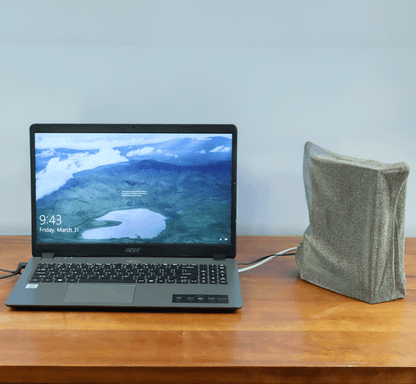 Acer laptop displaying aerial landscape on screen next to gray fabric WiFi Signal Tamer pouch on wooden desk.