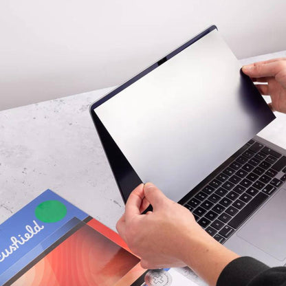 Person applying Ocushield Blue Light Screen Protector to MacBook Air, showing protective film being peeled back from screen.