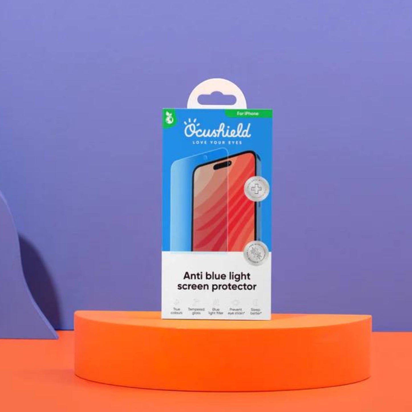 Ocushield Blue Light Screen Protector for iPhone packaged in blue box on orange platform against purple background.