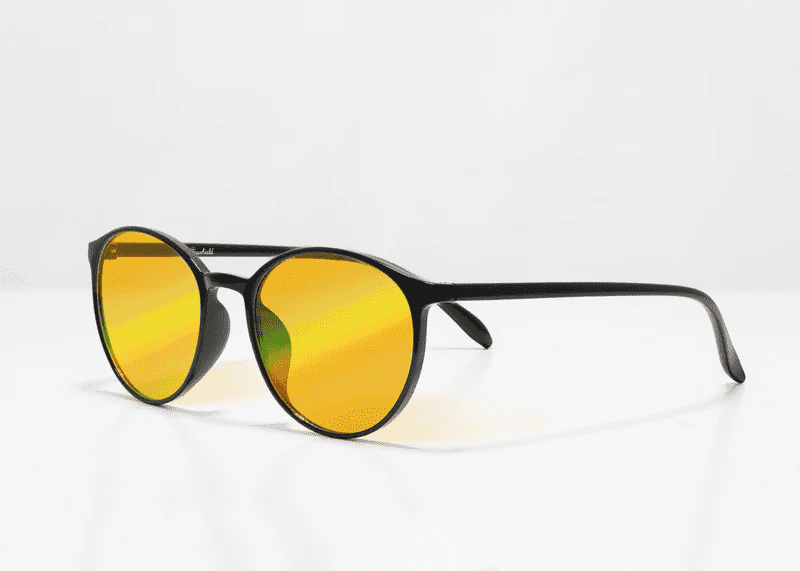 Ocushield Amber blue light glasses with black round frames and yellow-tinted lenses, displayed at a three-quarter angle against a white background.